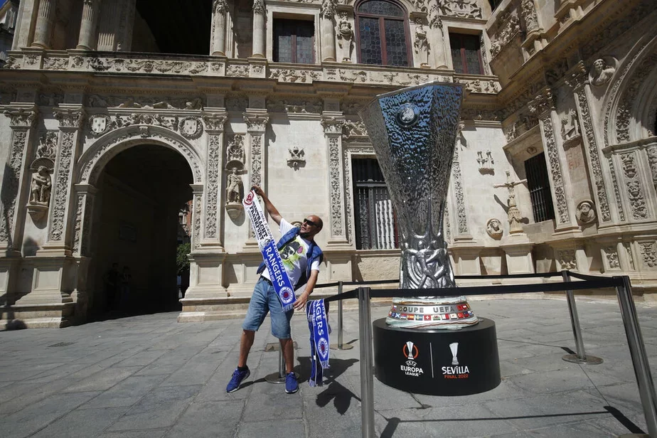 Болельщик стоит у копии трофея Лиги Европы в Севилье. Фото: АР